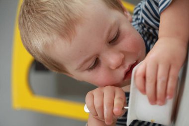 Komik bebek çocuk sarışın yalıyor parmak yoğurt ile