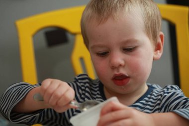 Komik bebek çocuk sarışın yalıyor parmak yoğurt ile