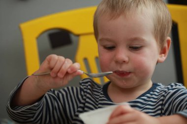 Komik bebek çocuk sarışın yalıyor parmak yoğurt ile