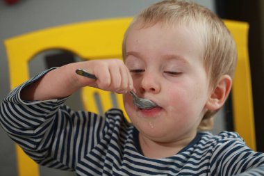 Komik bebek çocuk sarışın yalıyor parmak yoğurt ile