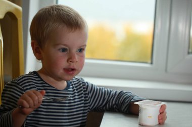 Komik bebek çocuk sarışın yalıyor parmak yoğurt ile