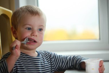 Komik bebek çocuk sarışın yalıyor parmak yoğurt ile