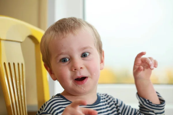 Funny babe boy blondes licks  finger with yogurt — Stock Photo, Image