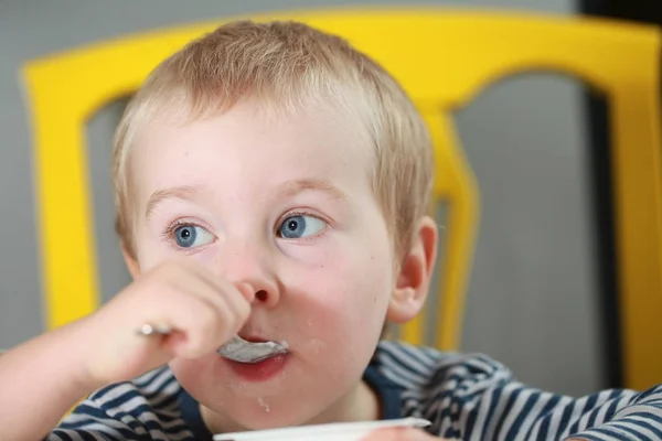 Divertido babe chico rubias lame dedo con yogur —  Fotos de Stock