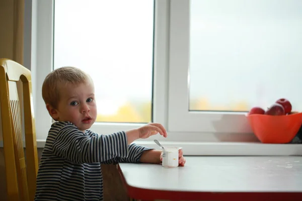 Funny babe boy blondes licks  finger with yogurt — Stock Photo, Image