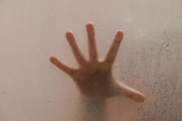 Baby pod prysznicem za szybą z kroplami — Zdjęcie stockowe