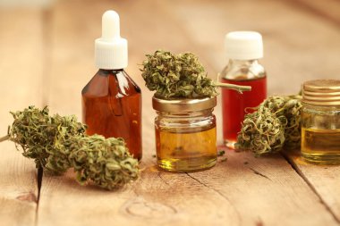 Ahşap bir masa üzerinde yeşil yaprakları ile özü yağı tıbbi esrar. Alternatif Tıp