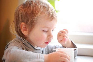 Çocuk masada oturan bir kaşık yoğurt yiyor