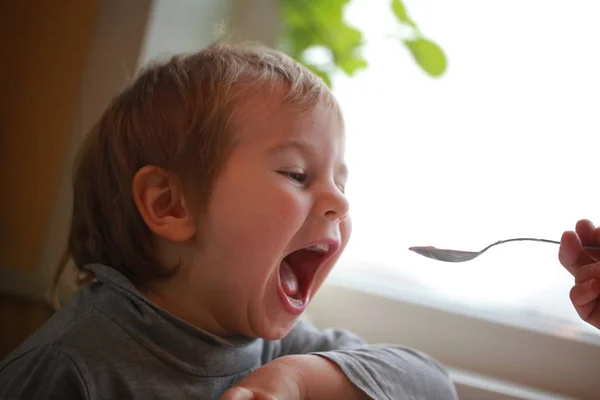 Criança Come Iogurte Com Uma Colher Sentada Mesa — Fotografia de Stock