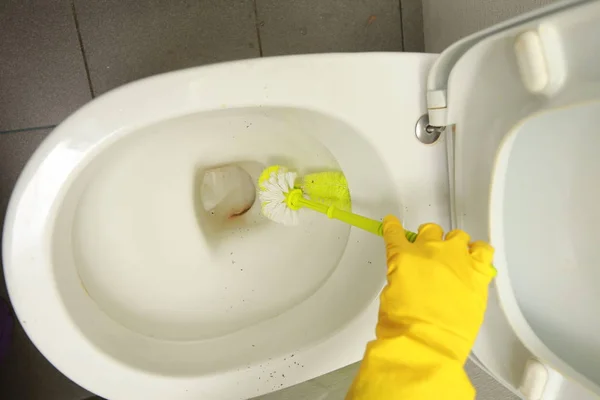 Mão em luvas amarelas lavagem do banheiro sujeira — Fotografia de Stock