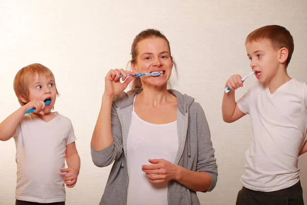Familia mamá y dos rubios chicos cepillarse los dientes —  Fotos de Stock