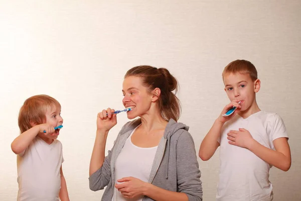 Familia mamá y dos rubios chicos cepillarse los dientes —  Fotos de Stock