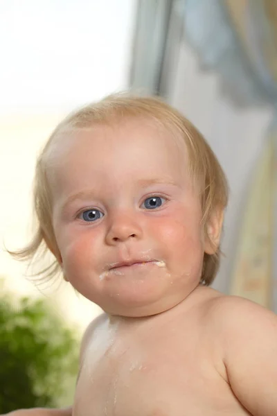 Vtipný baculatý blond chlapec krmení v kuchyni doma — Stock fotografie