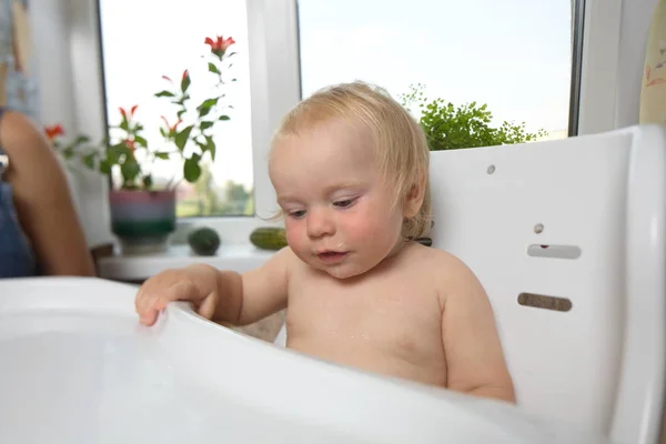 Funny chubby blond boy feeding in the kitchen at home — Stock Photo, Image