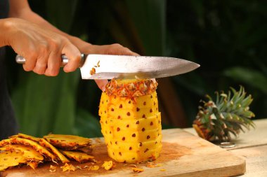 Taze olgun ananas doğrama kız elleri Tropik bir bahçe sri lanka 'sında ahşap bir masanın üzerinde