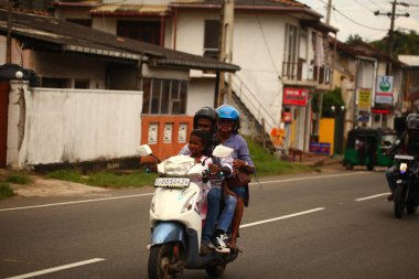 Asyalı bir aile gün boyunca yolda motosiklet sürüyor. Sri Lanka, Hikkaduwa, 2020