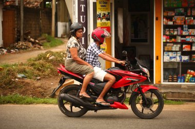 Asyalı bir aile gün boyunca yolda motosiklet sürüyor. Sri Lanka, Hikkaduwa, 2020