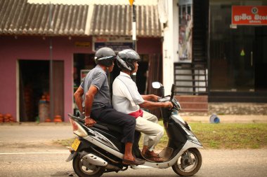 Asyalı bir aile gün boyunca yolda motosiklet sürüyor. Sri Lanka, Hikkaduwa, 2020