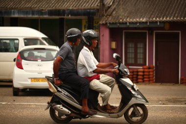 Asyalı bir aile gün boyunca yolda motosiklet sürüyor. Sri Lanka, Hikkaduwa, 2020