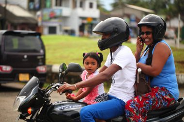 Asyalı bir aile gün boyunca yolda motosiklet sürüyor. Sri Lanka, Hikkaduwa, 2020