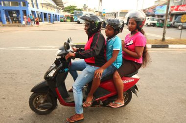 Asyalı bir aile gün boyunca yolda motosiklet sürüyor. Sri Lanka, Hikkaduwa, 2020