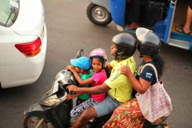 Asyalı bir aile gün boyunca yolda motosiklet sürüyor. Sri Lanka, Negombo, 2020