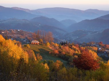 Dağlarda ahşap bir evi olan sonbahar manzarası