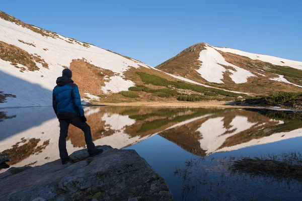 Paisaje de primavera con un turista cerca de un lago de montaña — Foto de Stock