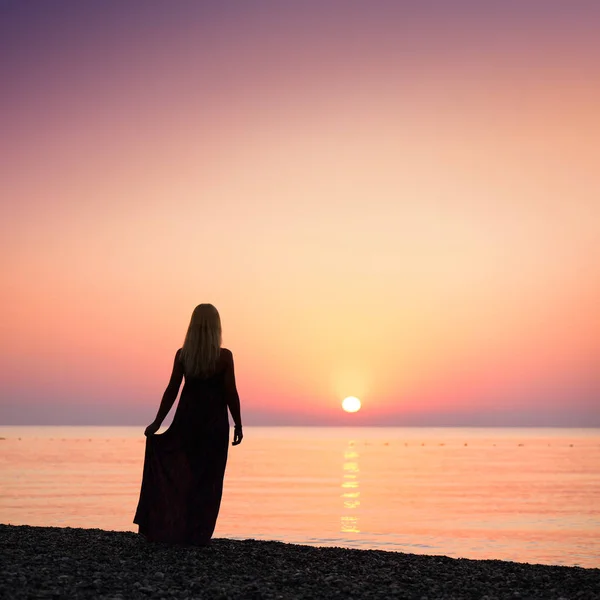 Pige på stranden ved solopgang - Stock-foto