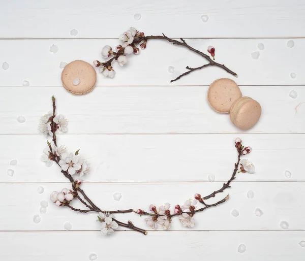 Decorative frame of flowers and macaroons on a white wooden back — Stock Photo, Image