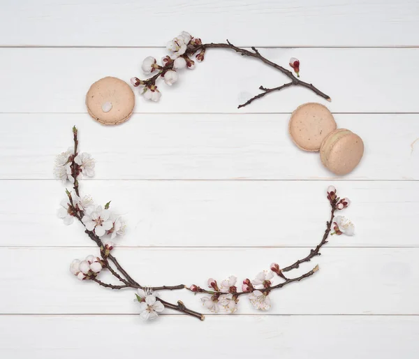 Decorative frame of flowers and macaroons on a white wooden back — Stock Photo, Image