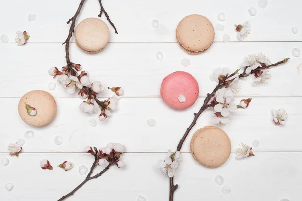 Makronenkekse und Blumen auf weißem Holzhintergrund — Stockfoto