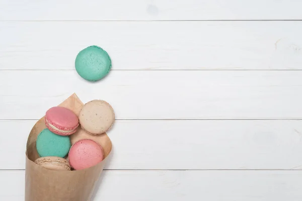 Package with colored macaroons on a white wooden background — Stock Photo, Image