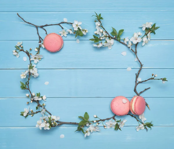 Kwiatowy macaroons ramki i deser na niebieskim tle drewnianych — Zdjęcie stockowe