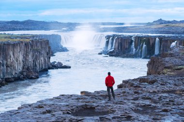 Turistik bir kırmızı ceketli Selfoss şelale görünüyor