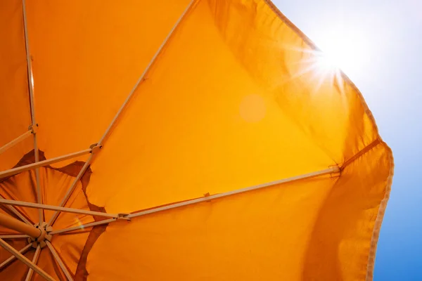 Yellow umbrella against the sun and blue sky — Stock Photo, Image