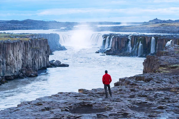 Tourist in roter Jacke blickt auf den selbstgebauten Wasserfall — Stockfoto