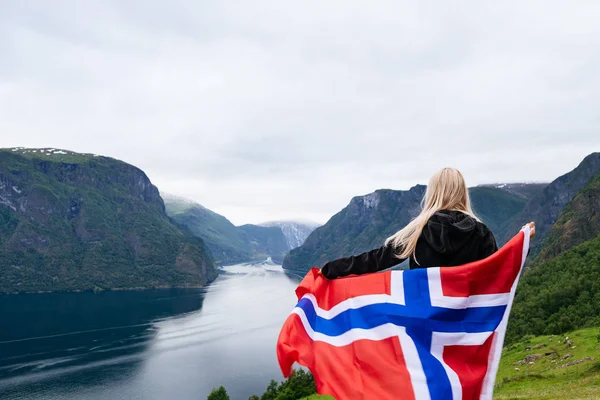 Menina com a bandeira da Noruega olha para o fiorde — Fotografia de Stock