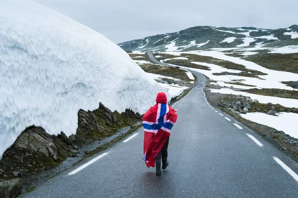 Mädchen mit norwegischer Flagge auf einer verschneiten Straße in Norwegen — Stockfoto