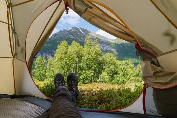 Mann schaut aus dem Zelt in die Berge — Stockfoto