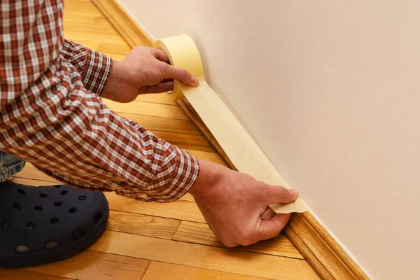 Master painter glues the masking tape on the baseboard — Stok fotoğraf