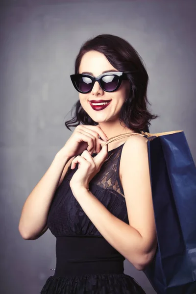 Kvinnan i svart klänning med shopping väska — Stockfoto