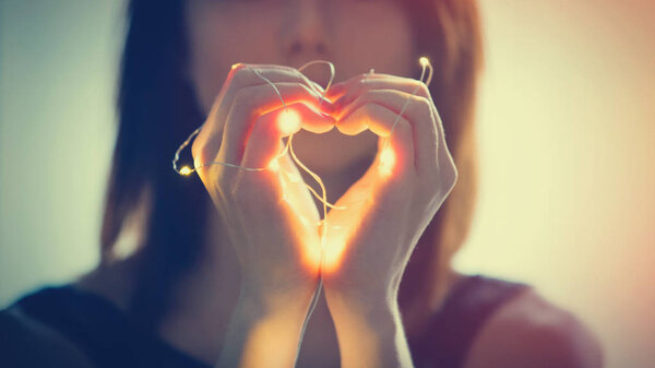 woman shownig heart with fairy lights