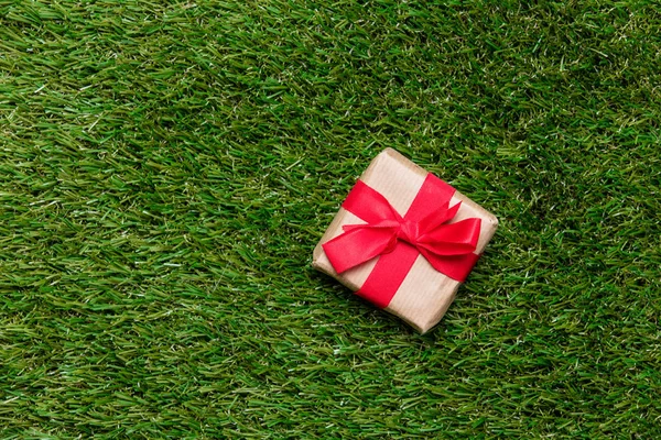 Pequeña caja de regalo roja sobre fondo de césped de hierba verde primavera — Foto de Stock