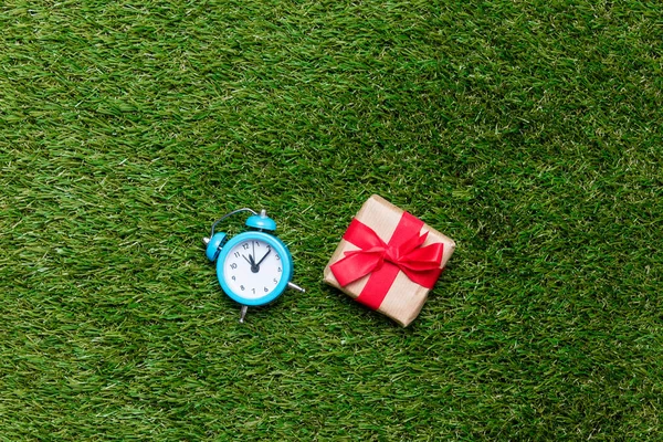 Petit réveil rétro et boîte cadeau sur fond d'herbe verte — Photo
