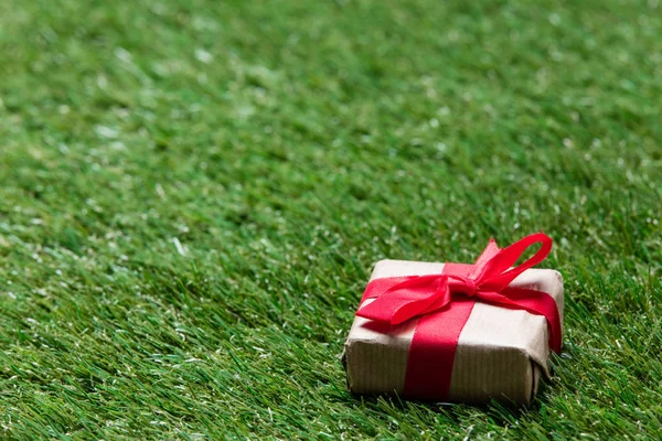 Pequeña caja de regalo roja sobre fondo de césped de hierba verde primavera — Foto de Stock