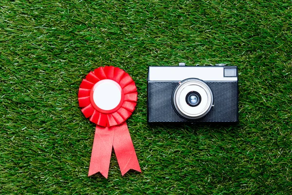 Récompense rouge et caméra vintage sur fond d'herbe verte — Photo