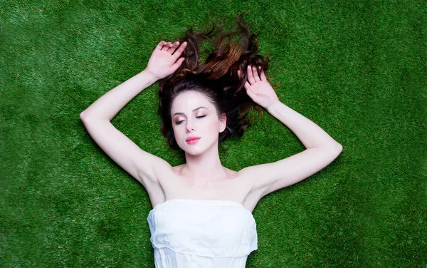 Портрет молодої рудої жінки, що лежить на зеленому весняному сірому — стокове фото