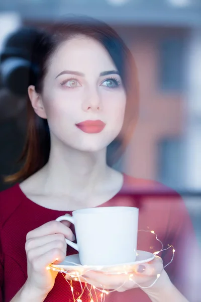 Vackra rednead kvinna med kopp kaffe eller cappuccino nära en — Stockfoto