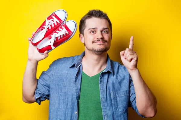 Hombre sosteniendo zapatos de goma rojos — Foto de Stock